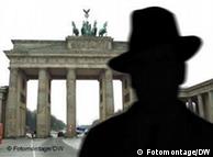 A man in a flop hat faces away from the camera at the Brandenburg Gate