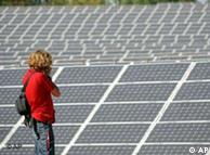 A woman takes photos of the solar fields of one of the world's largest solar power stations near Leipzig, Germany
