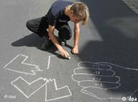 Молодой человек рисует на асфальте разорванную свастику и направленный на нее кулак в знак протеста против демонстрации неонацистов