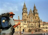 A man with a long walking stick stands in front of the a cathedral