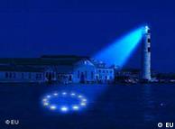 A lighthouse shines the image of a blue EU flag