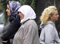 Two Turkish 
women wearing headscarves pass a woman not wearing a headscarf