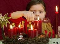 Mädchen zündet rote Kerze eines Adventskranz an. (Quelle: dpa)