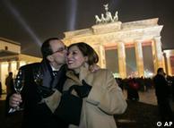 Two people kiss in front of the Brandenburg Gate