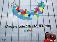 An volunteer stands in front of the logo of the Universiade Games at the Shenzhen Bay Sports Center before the opening ceremony for the 26th Universiade games in Shenzhen, China, Friday, Aug. 12, 2011. (AP Photo/Vincent Yu)