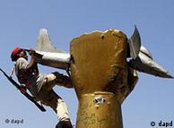 A rebel fighter climbs on top of a statue inside Moammar Gadhafi's compound 