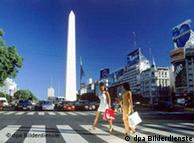 Zwei Frauen mit Einkaufstaschen überqueren vor dem Obelisken die Avenida 9 de Julio in Buenos Aires. Undatiert.