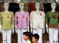 Chinese shoppers walk by a store window with mannequins 