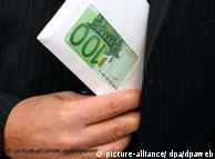 A hand puts a wad of 100-euro notes into a jacket pocket