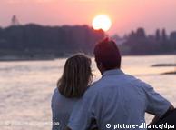Couple standing close together in front of sunset over the Rhine River