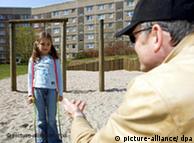 A man beckons to a young girl on a  playground
