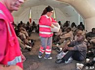 Red Cross workers in red safety jackets handing out biscuits to African migrants
