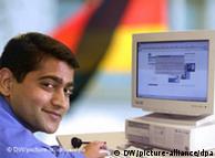 indian man sitting at computer with germany flag