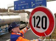 A man installs a speed limit sign on the autobahn