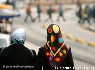 Two women with headscarves walk down a street