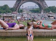 A boy plays in the Trocadero fountain as two women sunbathe in Paris
