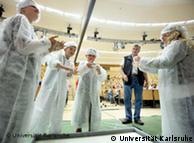 Children dressed in white lab coats and hair protectors play with a sticky white mass