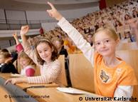 Children stick their hands in the air to ask a question at the Karlsruhe Children's University