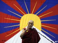 Dalai Lama standing in front of a Tibetan flag