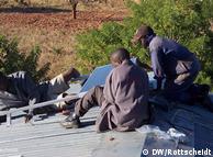 Insatalando placas solares sobre el tejado de una escuela en Zambia.