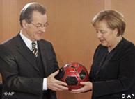 Merkel hands Müntefering a soccer ball in red and black