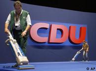 People vacuum the floor in front of a CDU logo