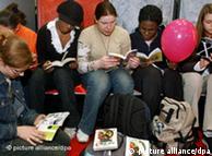 Teenage women reading books on the floor of the Leipzig Book Fair.