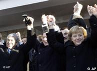 European leaders, clad in black coats, link arms and cheer