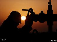 An unidentified worker turns a valve along a oil pipeline at dusk in Sakhir, Bahrain. 