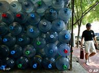 Ein Mann läuft an aufeinander gestapelten Flaschen mit Trinkwasser vorbei (Archiv, Quelle: AP)