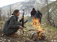 A PKK rebel warms herself by a fire