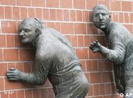 Sculptures of people listening to a wall