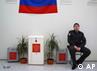 A Russian police officer sits next to an election urn that stands between to miniature palms