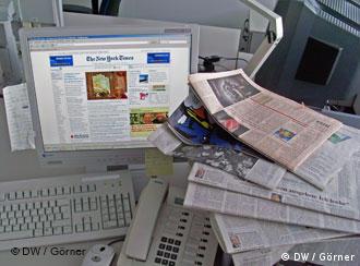 Газеты возле компьютера с открытим вебсайтом 