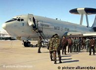 Military personnel stand next to an AWACS early warning radar plane 