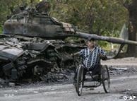 Ein  verwundeter Mann im Rollstuhl vor einem zerstörten Panzer (Foto: AP)