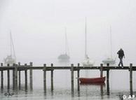 A man walking on a bridge in cloudy weather with boats in the background