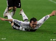 German soccer player laying on grass with arms spread out in celebration