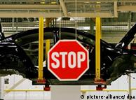 A stop sign infront of a car production line