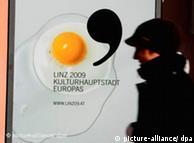 A man walks by a poster for Linz as cultural capital that has a fried egg on it