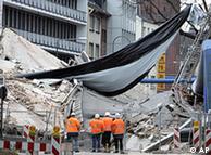 workmen standing in front of collapsed building