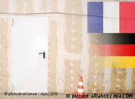 A French and German flag, on a wall next to a closed door.