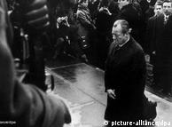 Willy Brandt kneels before a Holocaust memorial in front of a crowd of onlookers