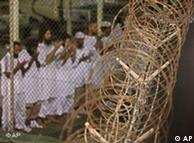 Guantanamo detainees pray near a fence of razor-wire.