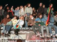 Singend und schunkelnd freuen sich junge Menschen auf der Berliner Mauer über die Grenzöffnung (Archivbild vom 10.11.1989). Die Hoffnung für viele DDR-Bürger hieß im Sommer 1989 Ungarn. Im Trabi, Wartburg oder per Zug machten sie sich unauffällig auf den Weg in die Freiheit - immer in Angst, auf der Flucht in den Westen zu zeitig entdeckt zu werden. Am 9. November 1989 fiel dann die Mauer. Jetzt jährt sich das historische Ereignis zum 15. Mal. Foto: Peter Kneffel dpa (zum dpa-Korr.-Bericht 