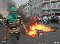 A masked supporter of Iranian reformist presidential candidate Mir Hossein Mousavi walks past burning rubbish