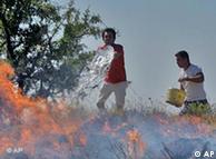 A man throws a pail of water over the fire at the village of Varnavas near the town of Marathon