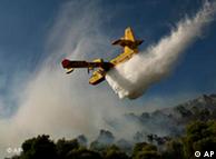 An aircraft dropping water on a burning forest in Greece