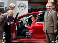 Angela Merkel sits in a red Opel Astra