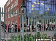 People wait in line in front of an EU flag